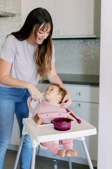 Baby wearing silicone bib with food catcher pocket. 
