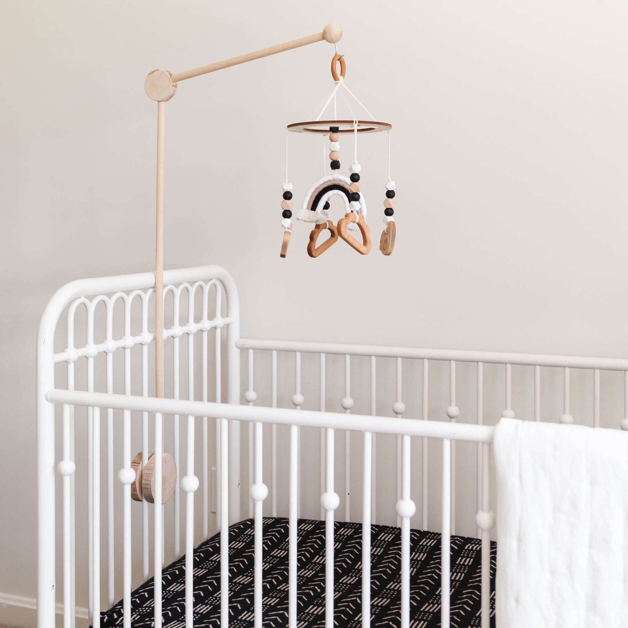 White crib with a black and white patterned mattress in a nursery setting.