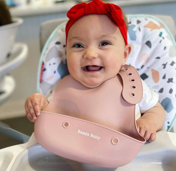 Baby wearing silicone bib with food catcher pocket. 