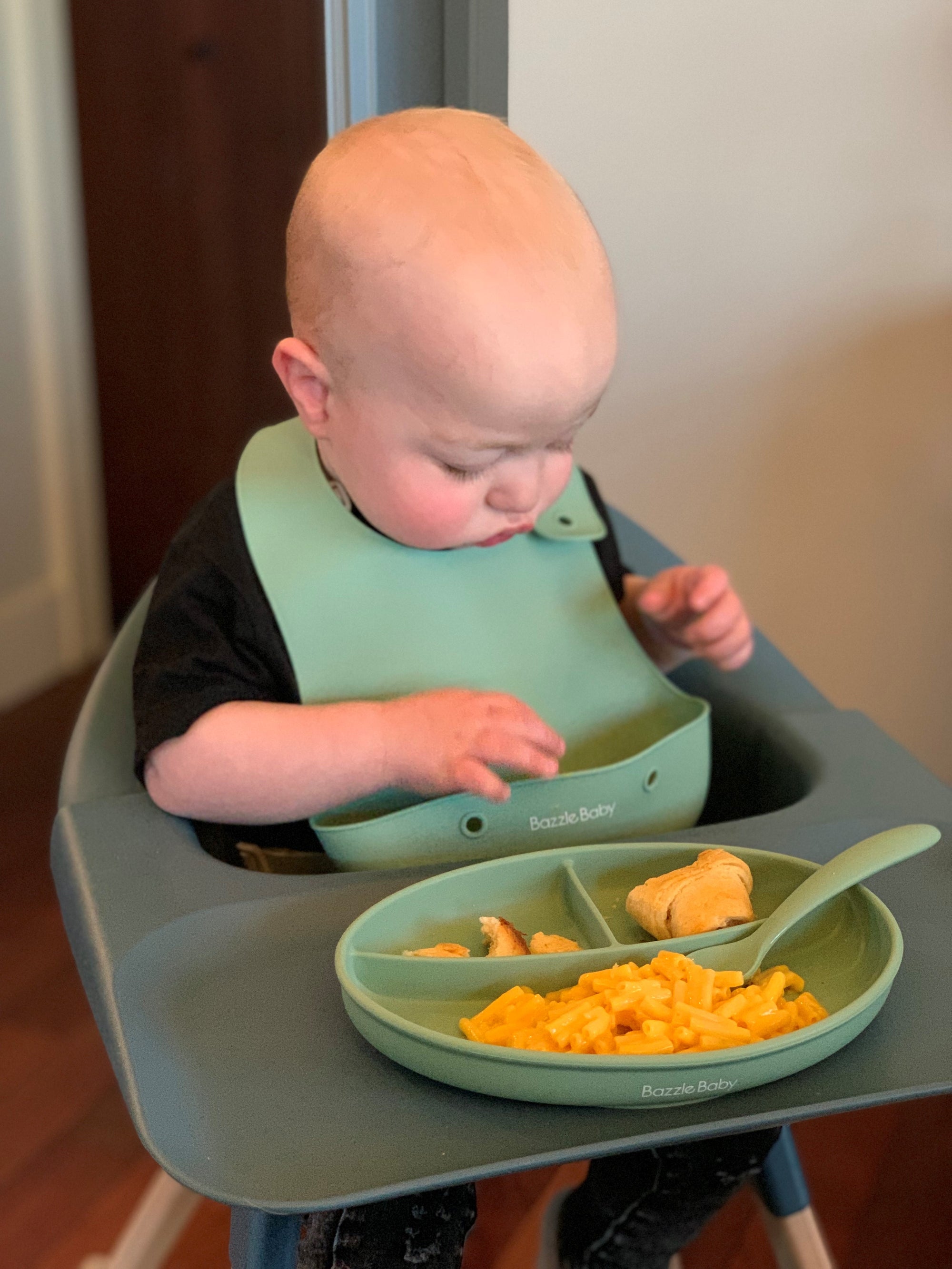 Baby wearing silicone bib with food catcher pocket. 