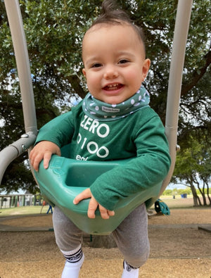 Baby wearing infinity scarf drool bib in green dots.