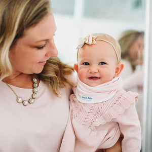 Baby wearing infinity scarf drool bib in pink and white stripes.