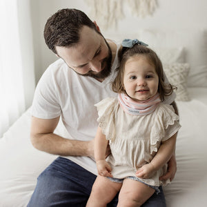 Baby wearing infinity scarf drool bib in pink and white stripes.