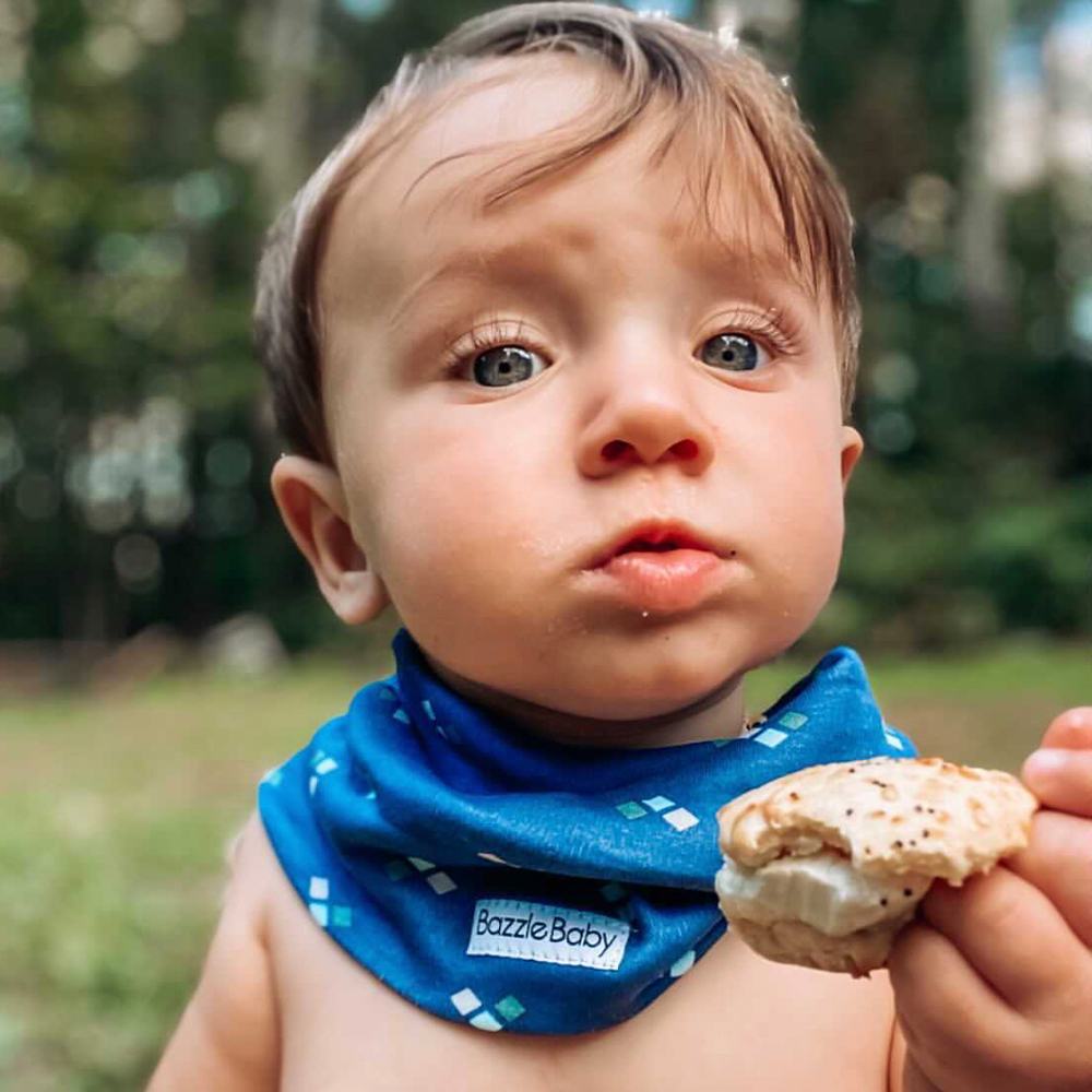 Baby wearing infinity scarf drool bib in navy diamonds.