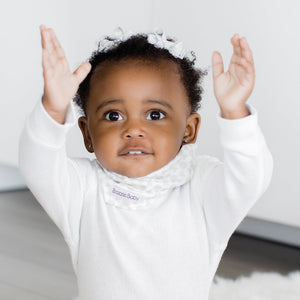 Baby wearing infinity scarf drool bib in white.