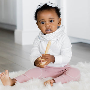 Baby wearing infinity scarf drool bib in white.