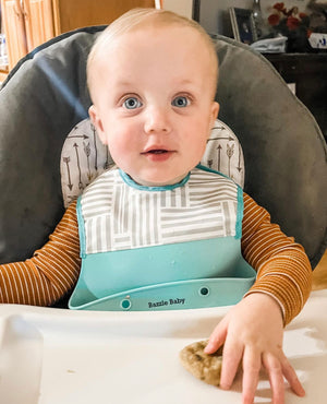 Baby wearing silicone bib with food catcher pocket. 